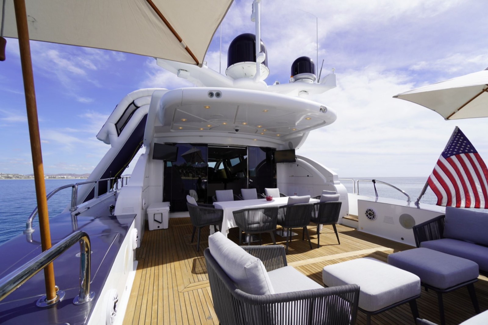 Aft deck of a crewed luxury charter yacht in Los Cabos, dining table set under shade
